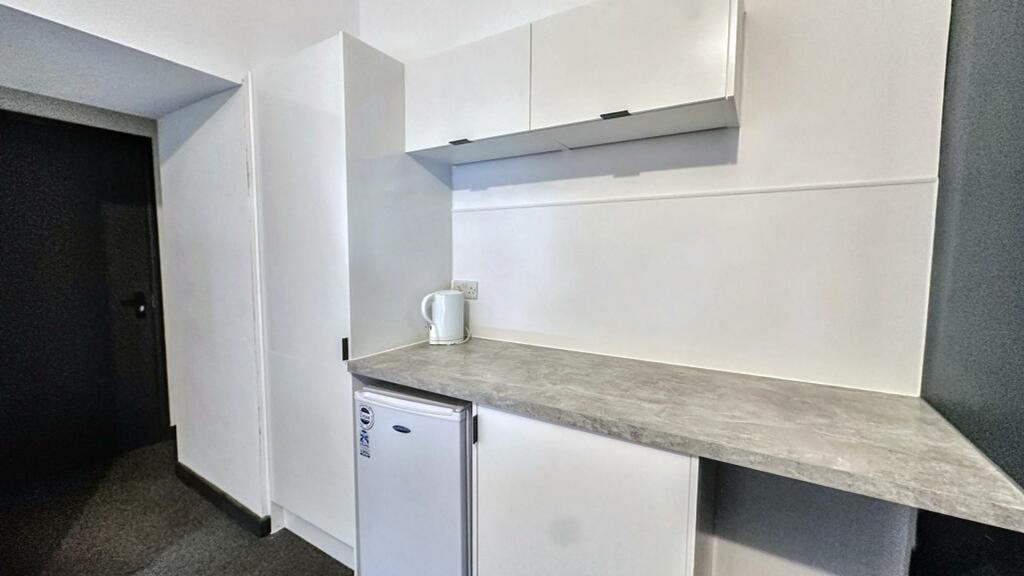 A clean and modern kitchenette with ample stora...