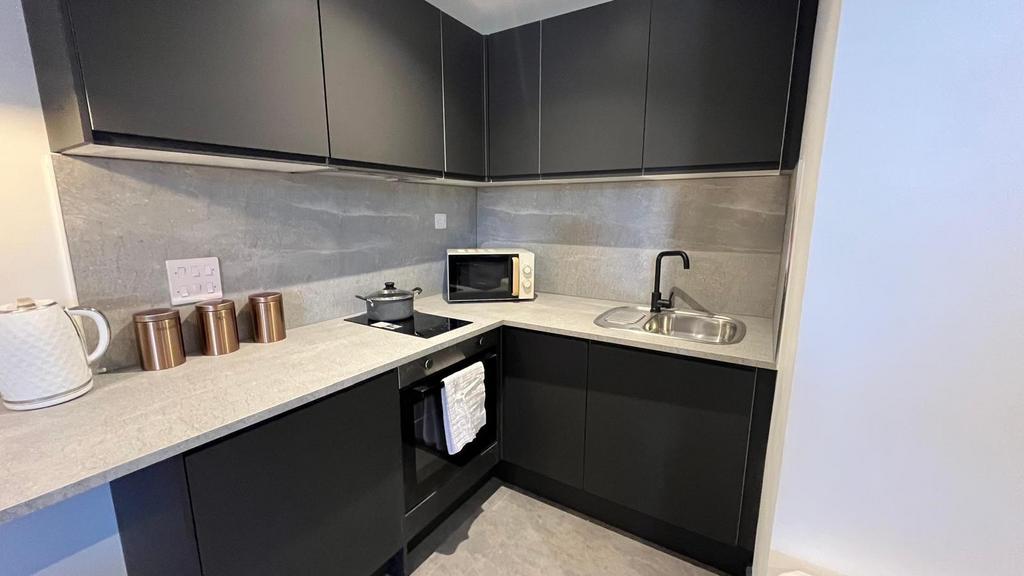 A sleek modern kitchen with dark matte cabinets...