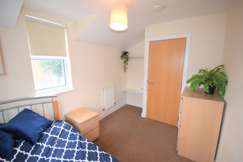 A bright and tidy double bedroom with a cozy at...