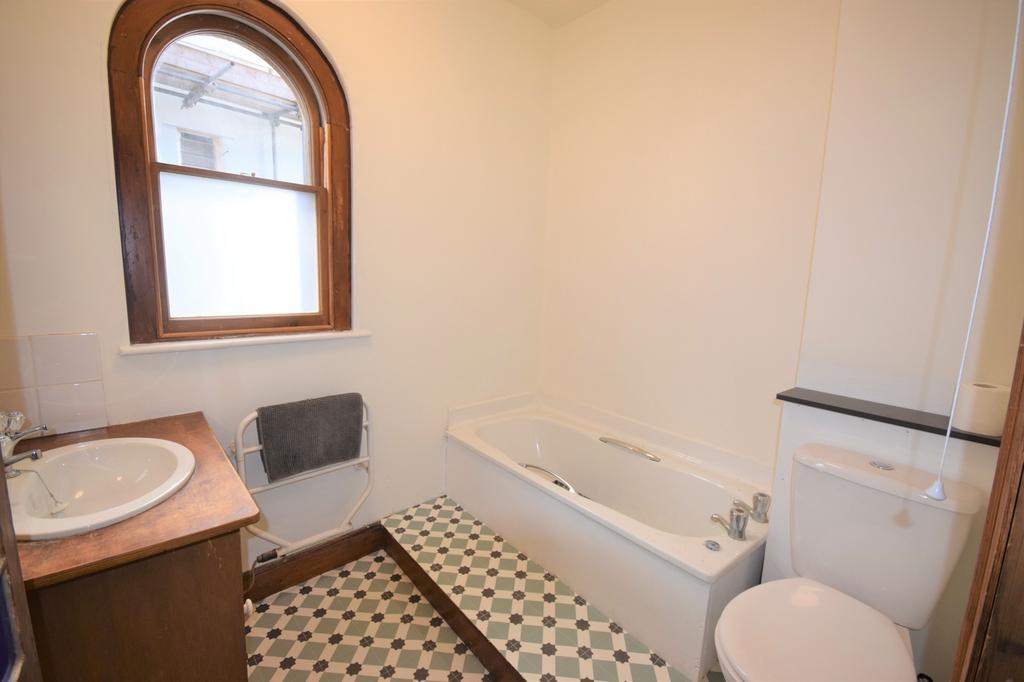 A clean and bright bathroom featuring a bathtub...