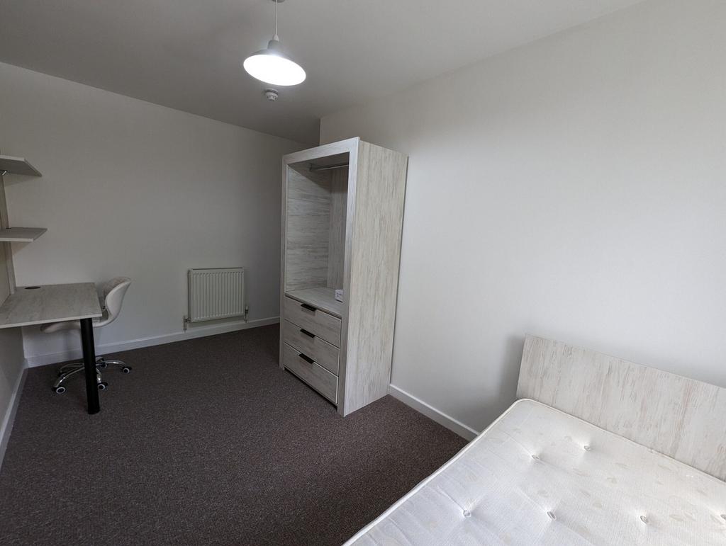 A spacious and tidy double bedroom featuring a ...