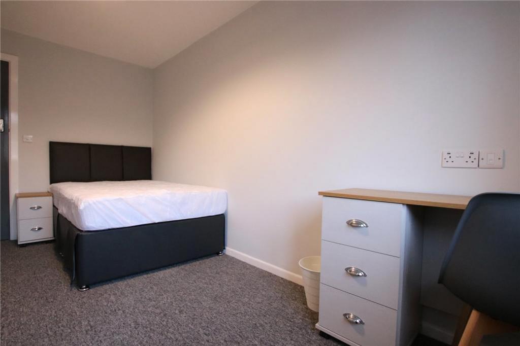 A spacious and tidy double bedroom featuring a ...