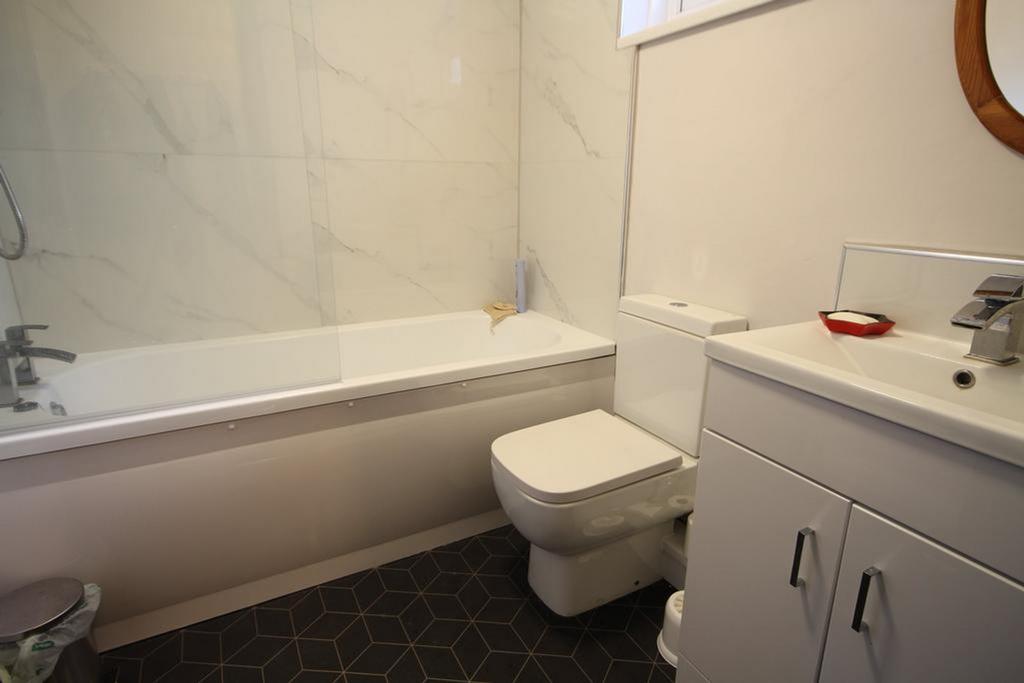 A modern and tidy bathroom featuring a bathtub ...