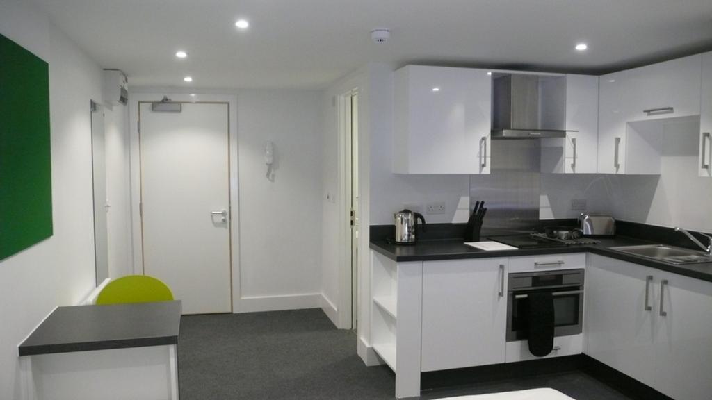 A modern kitchenette with sleek white cabinets ...