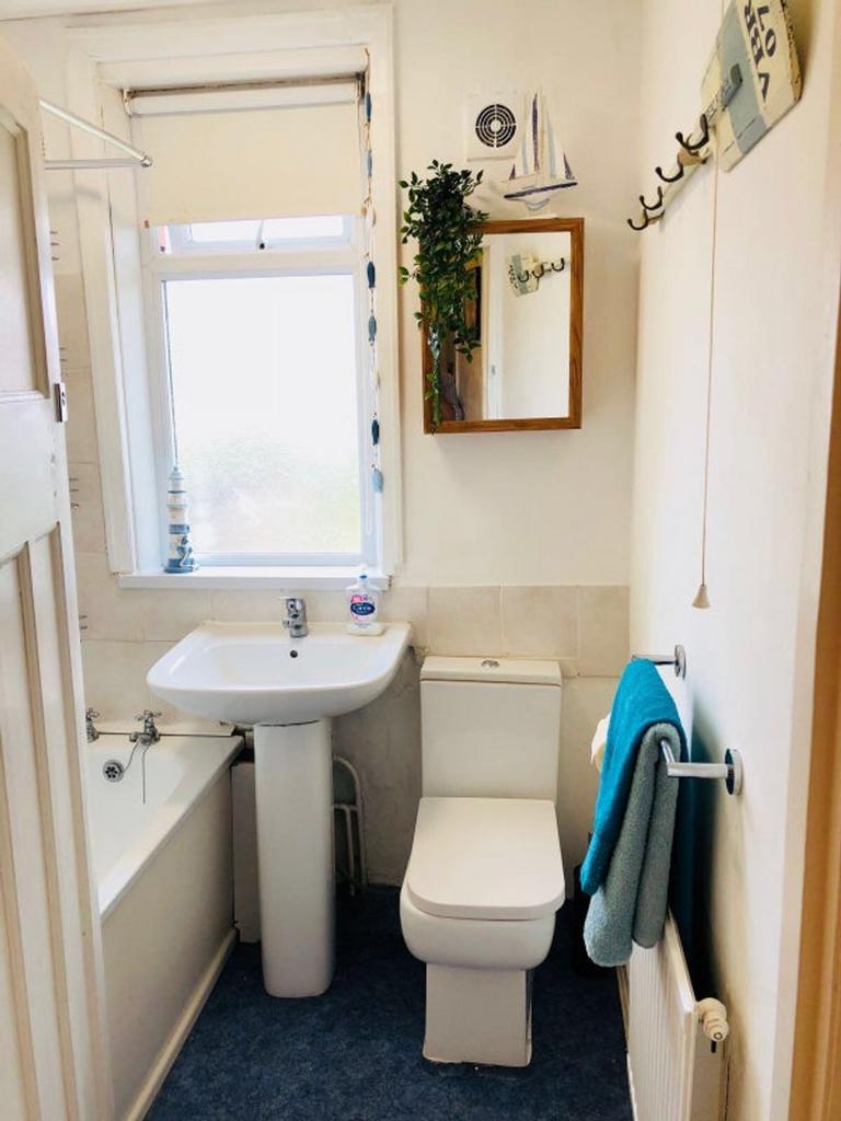 A bright and tidy bathroom featuring a bathtub ...