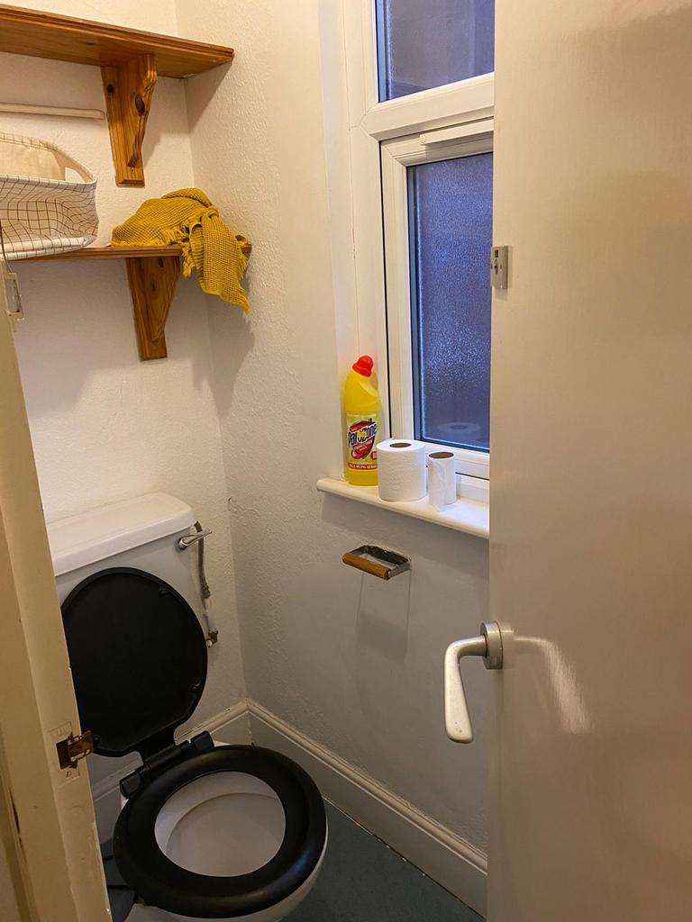 A tidy single toilet with essential amenities a...