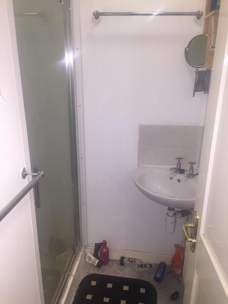 A compact bathroom featuring a shower and sink,...