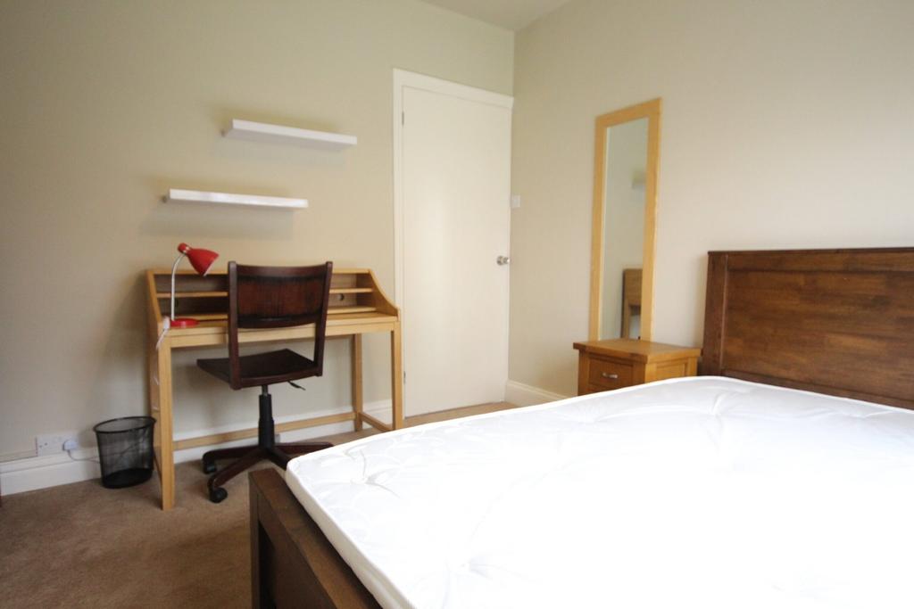 A spacious double bedroom with a desk and chair...
