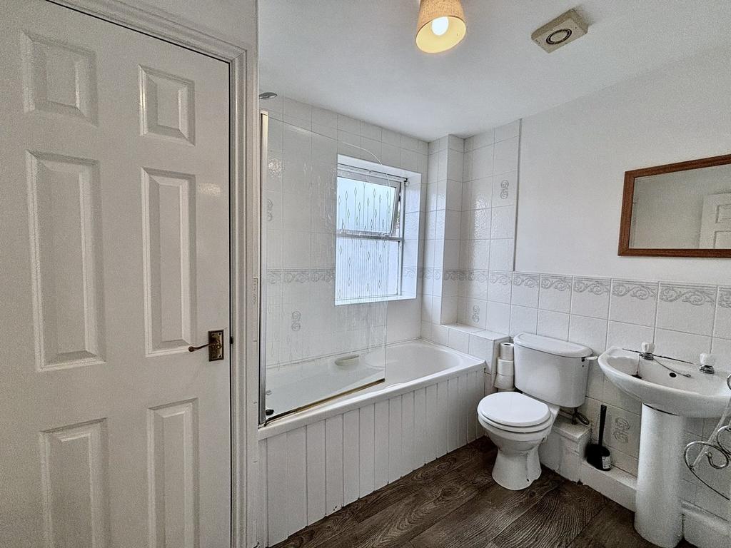 A bright and clean bathroom featuring a bathtub...