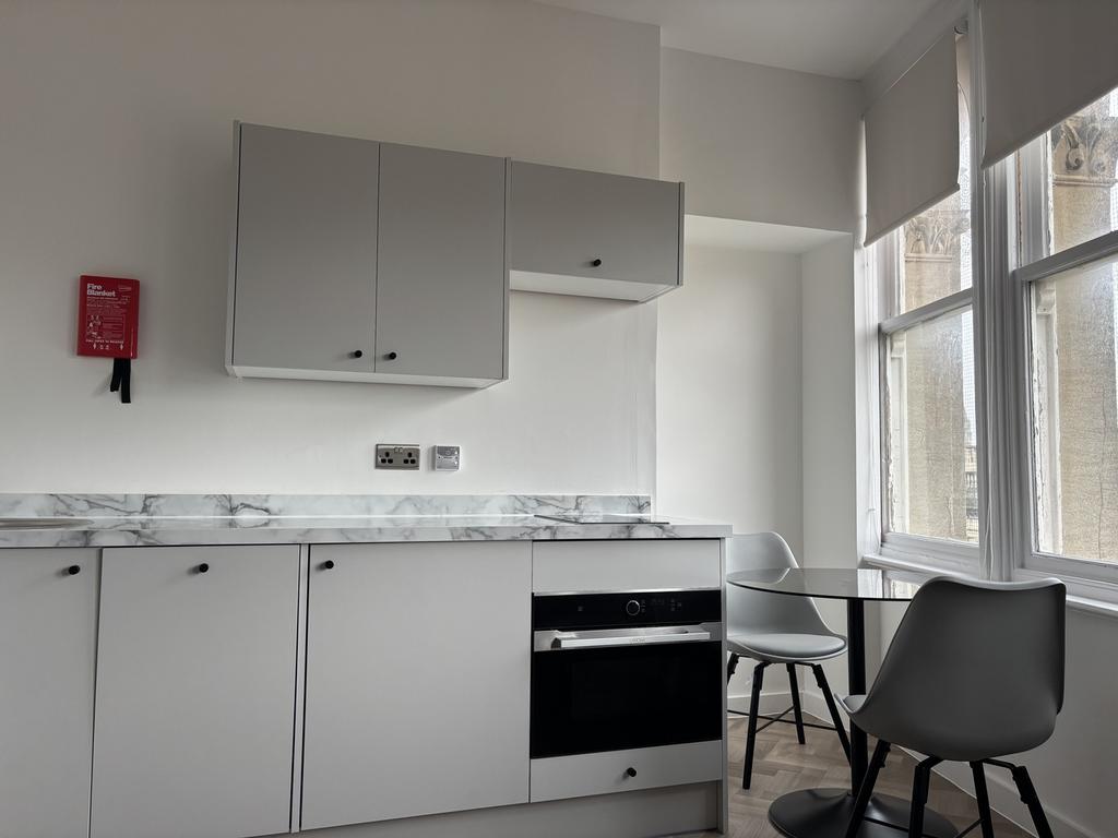 A modern and clean kitchenette with ample natur...