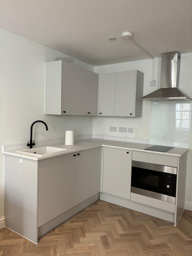 A modern and tidy kitchenette with sleek cabine...