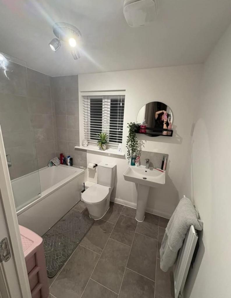 A modern and tidy bathroom featuring a bath and...