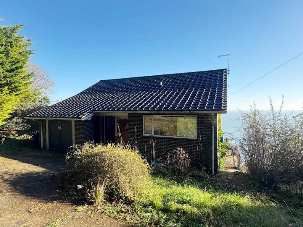 A front view of the home with the sea beyond