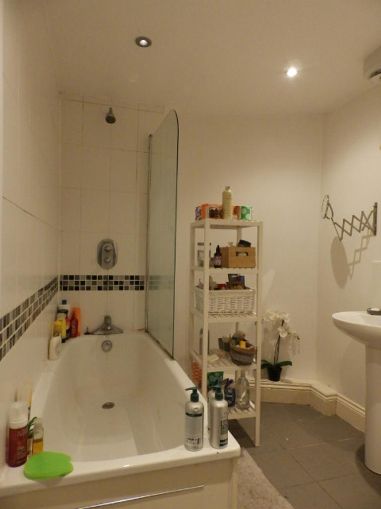 A clean and spacious bathroom featuring a batht...