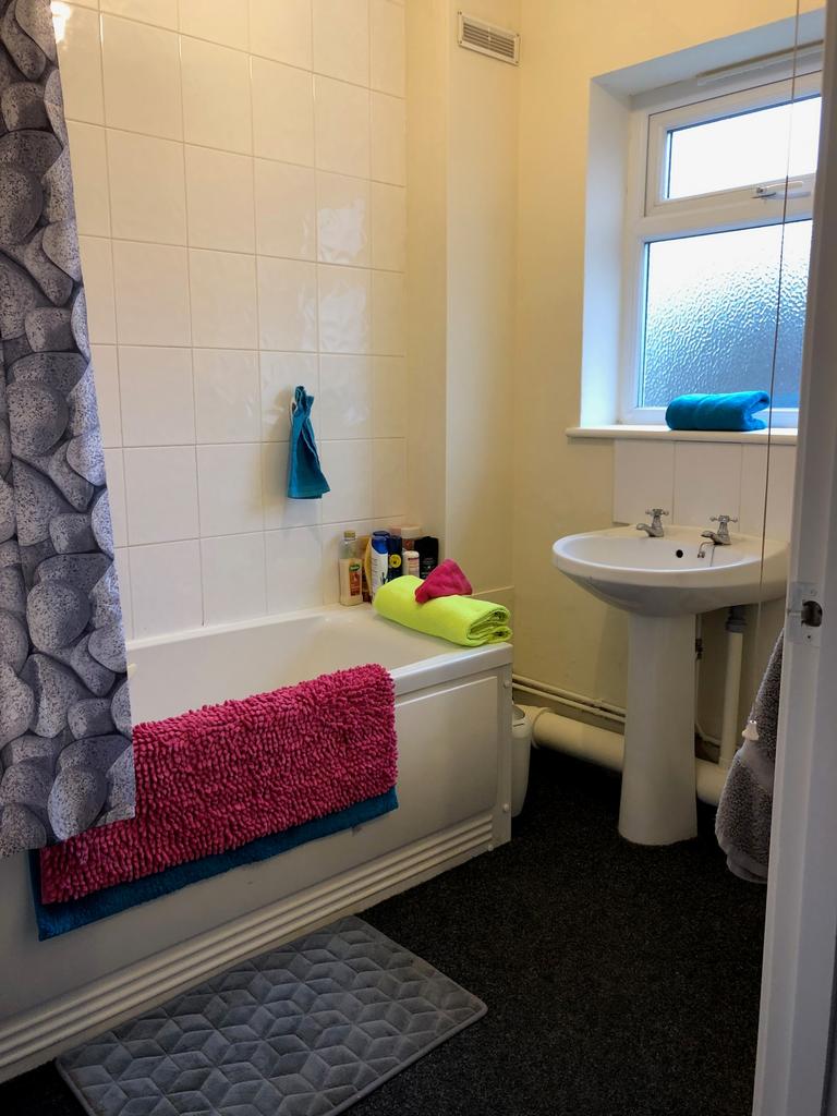 A clean and bright bathroom featuring a bathtub...