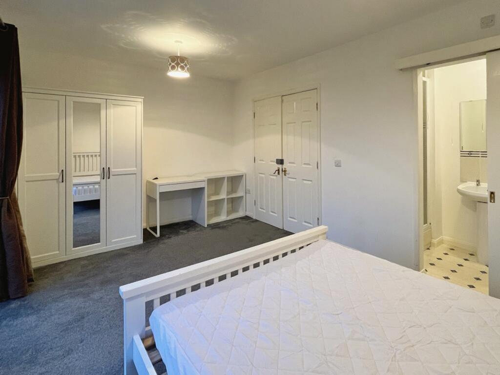 A spacious and well-lit double bedroom with a f...