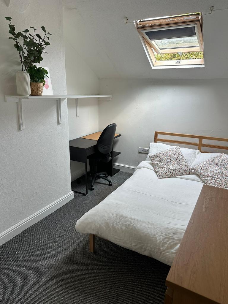 A cozy single bedroom featuring a neatly made b...