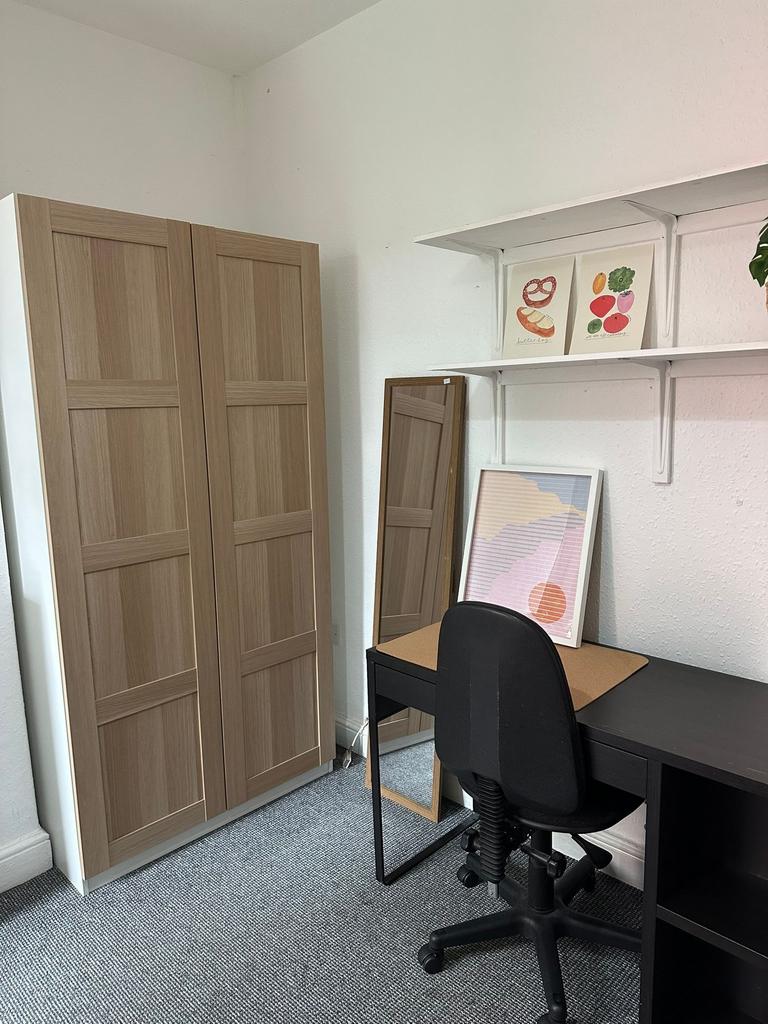 A well-organized student room featuring a wardr...