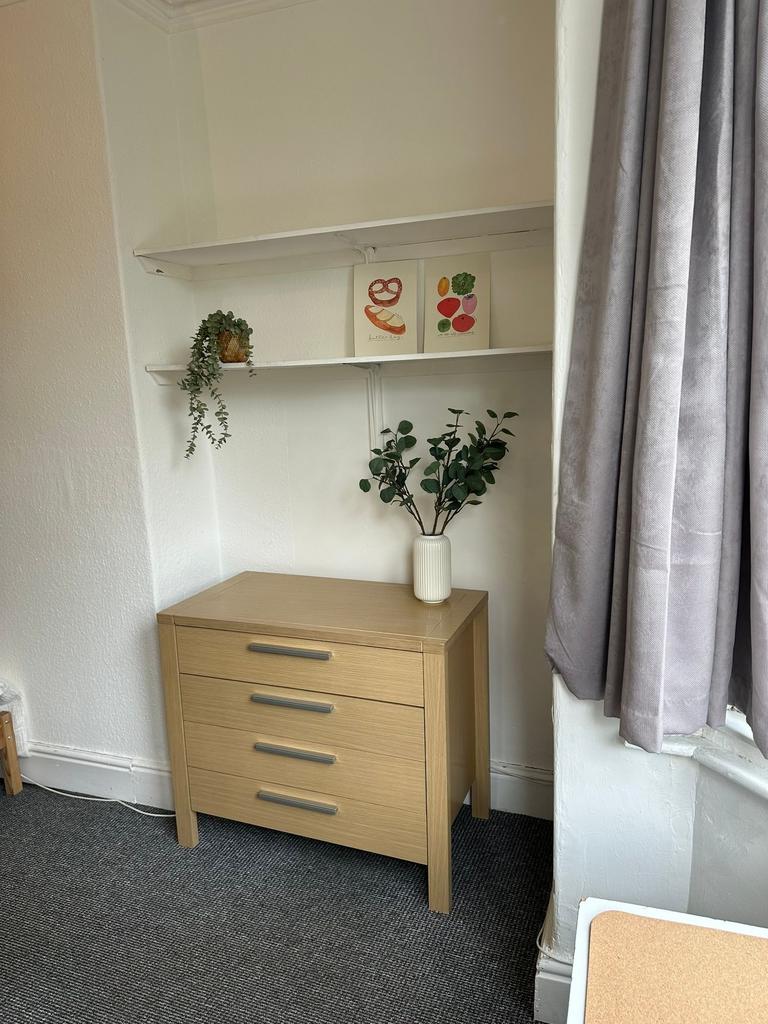 A cozy bedroom featuring a sleek wooden chest o...