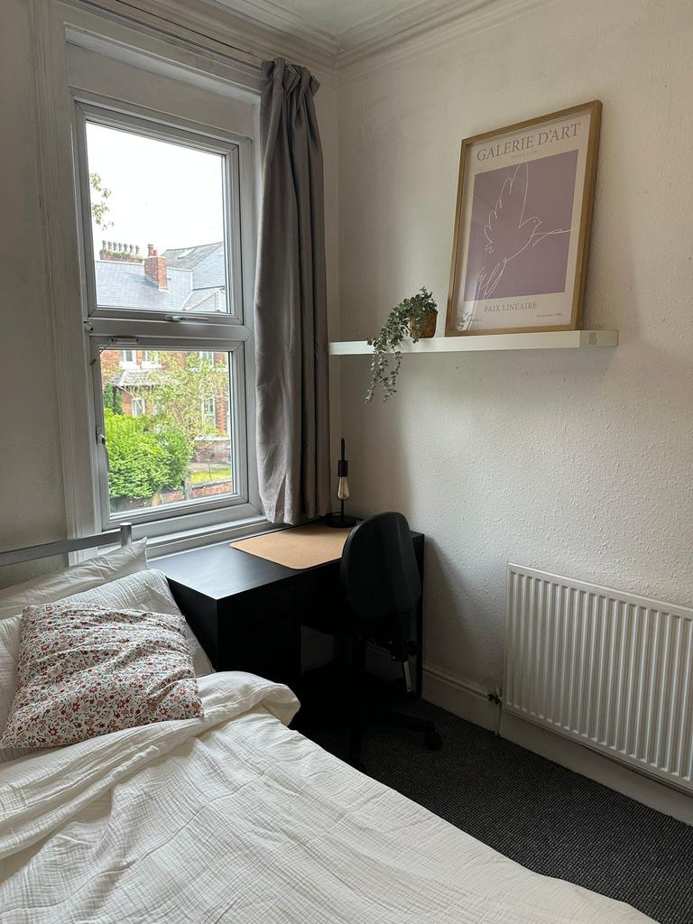 A cozy single bedroom featuring a comfortable b...