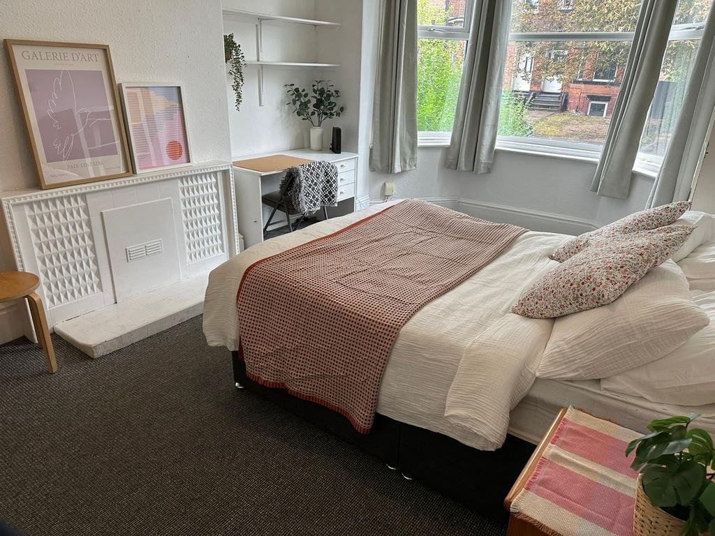 A bright and welcoming bedroom featuring a comf...