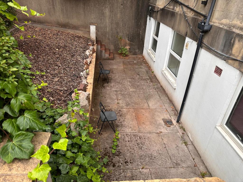 Private paved rear courtyard with two chairs, b...