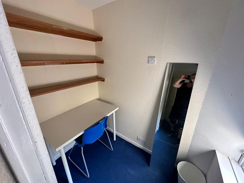 Compact room with a study desk, shelving and a ...