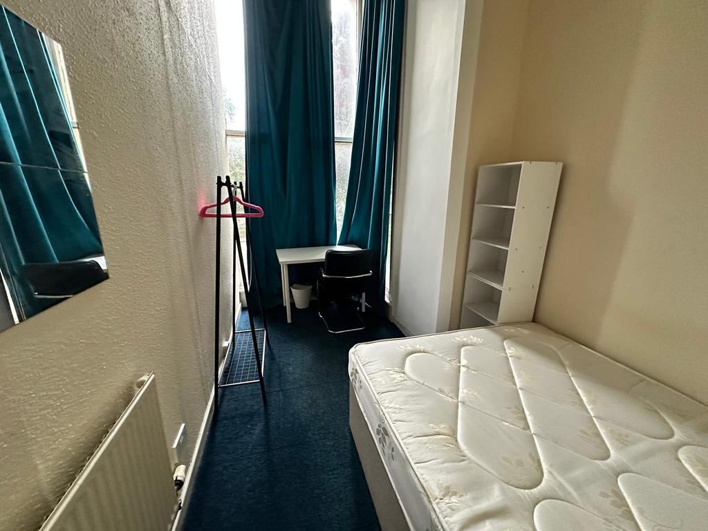 Bright single bedroom with tall windows, teal c...