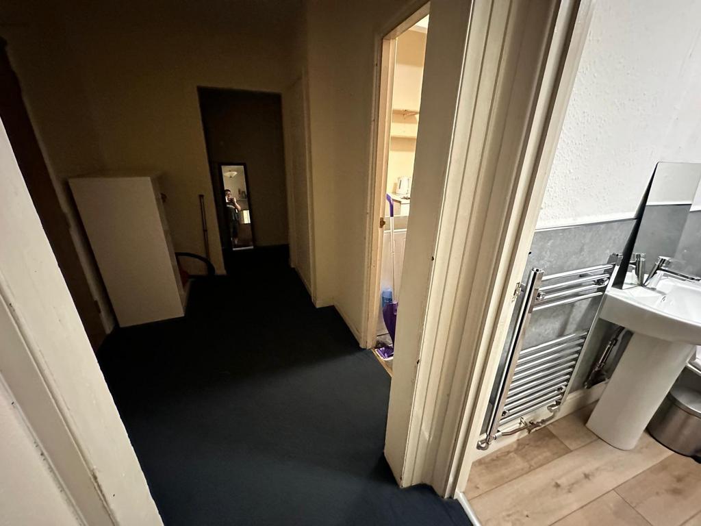 Narrow interior hallway with dark carpet leadin...