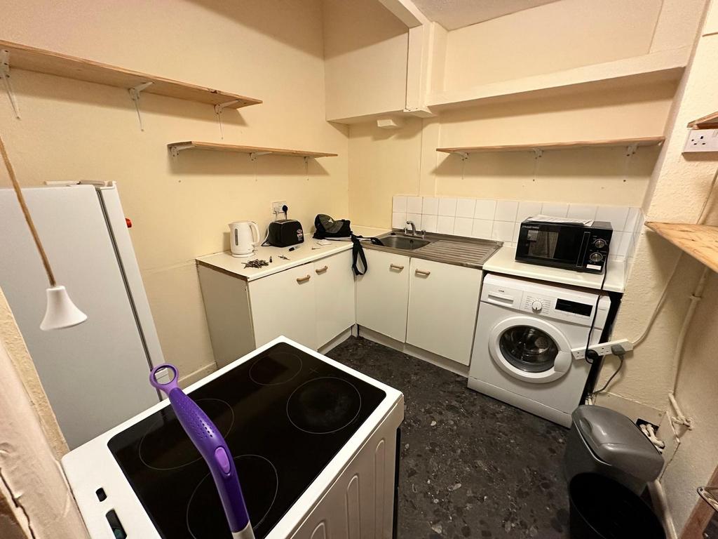 Compact fitted kitchen with white cabinets, int...