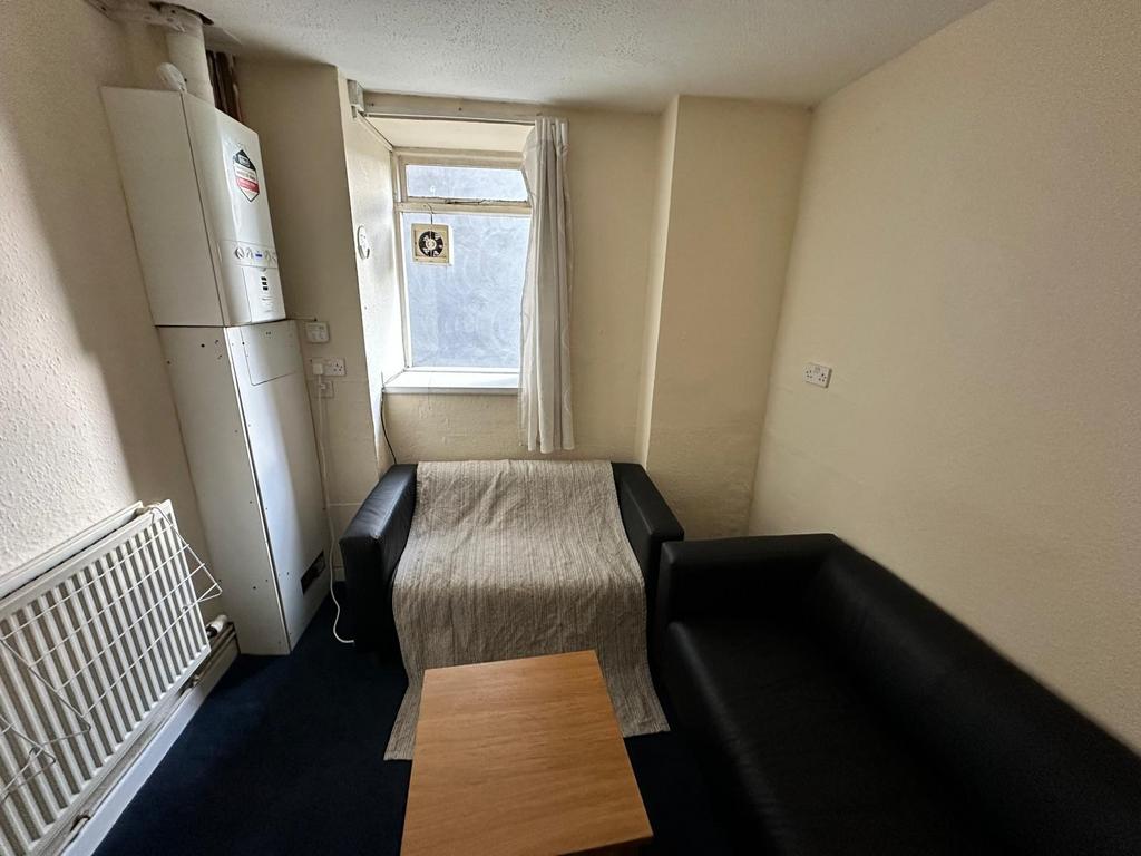 Cosy communal lounge with two black sofas, a sm...