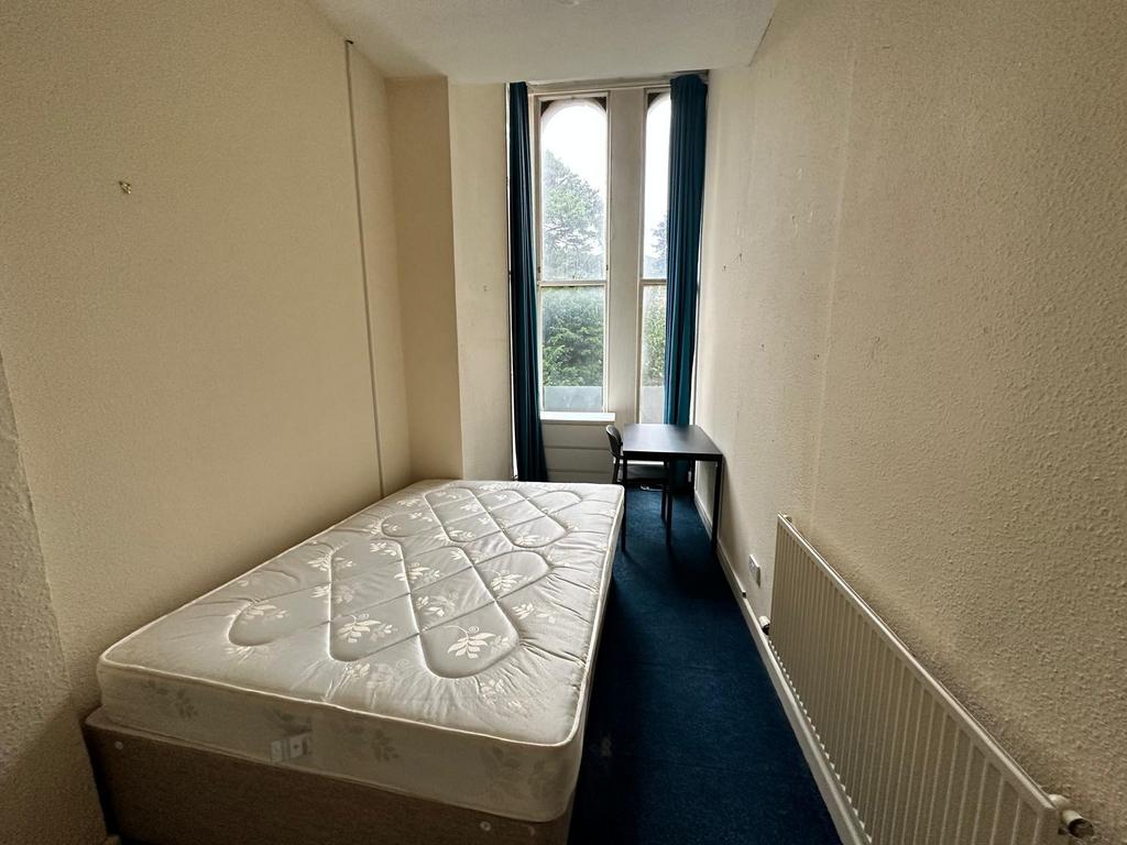 Neat, narrow bedroom with a single bed position...