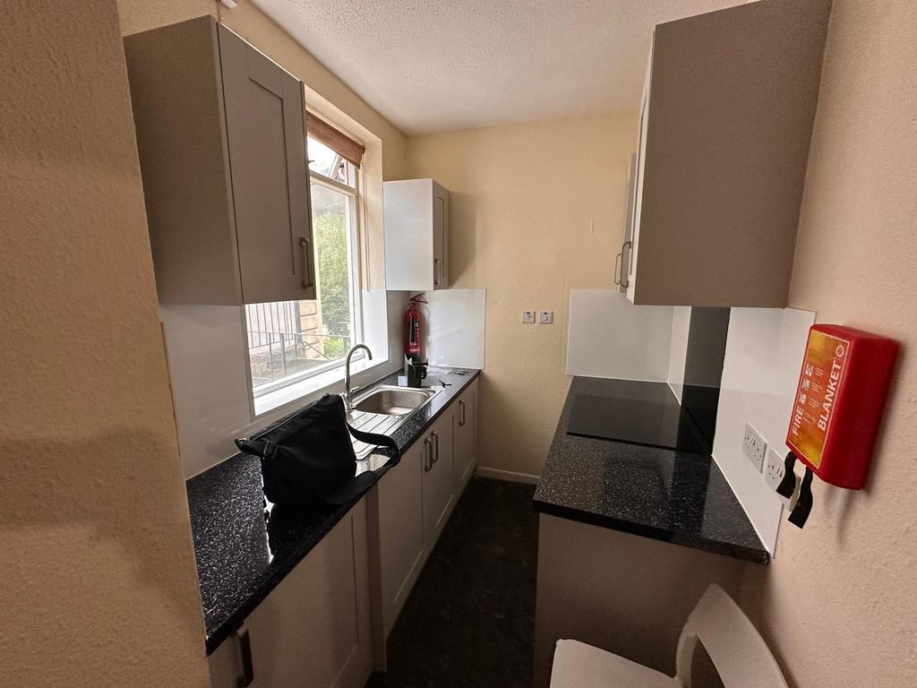 Compact galley-style kitchen with dark speckled...