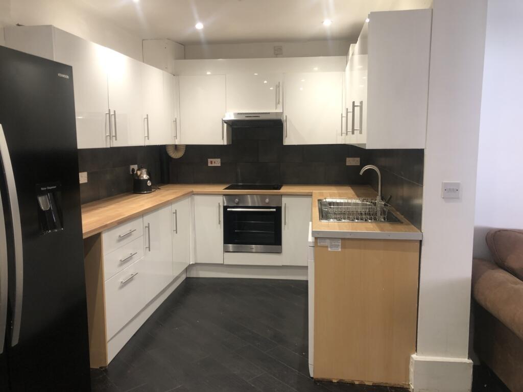 Modern kitchen featuring sleek white cabinets, ...