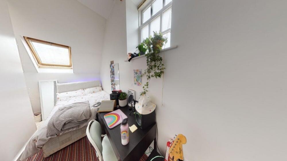 Cozy single bedroom with a skylight and window ...