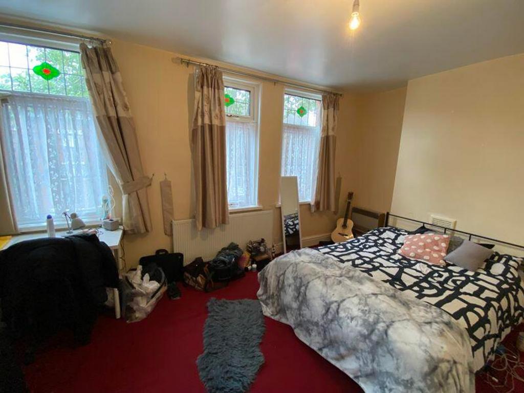 A spacious double bedroom featuring large windo...