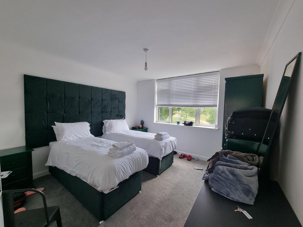A tidy double bedroom featuring two single beds...