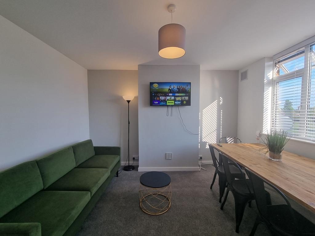 A modern living room with a green sofa, a dinin...
