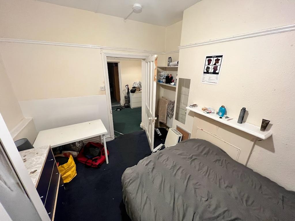 A cozy double bedroom with a desk and storage, ...