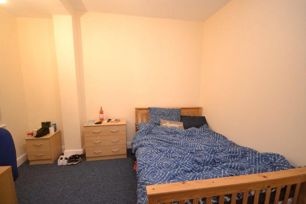 A modest double bedroom with a blue patterned b...