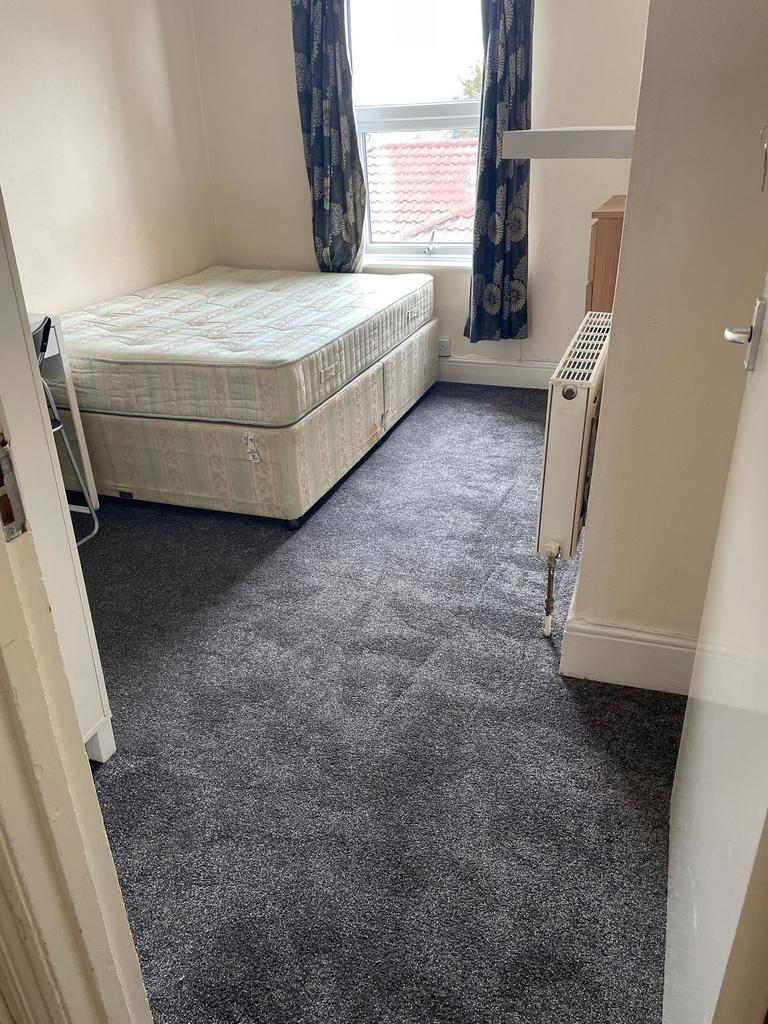 A modest bedroom featuring a single bed with a ...