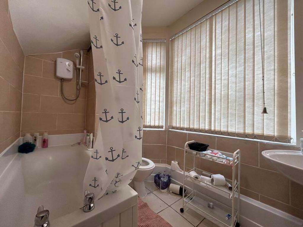 A bright and clean bathroom featuring a bathtub...