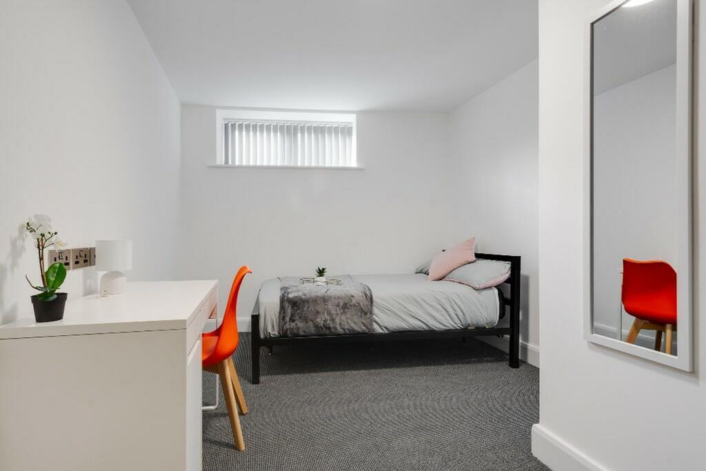 A clean and modern single bedroom featuring a c...