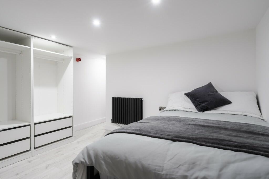 This modern double bedroom features a cozy bed,...