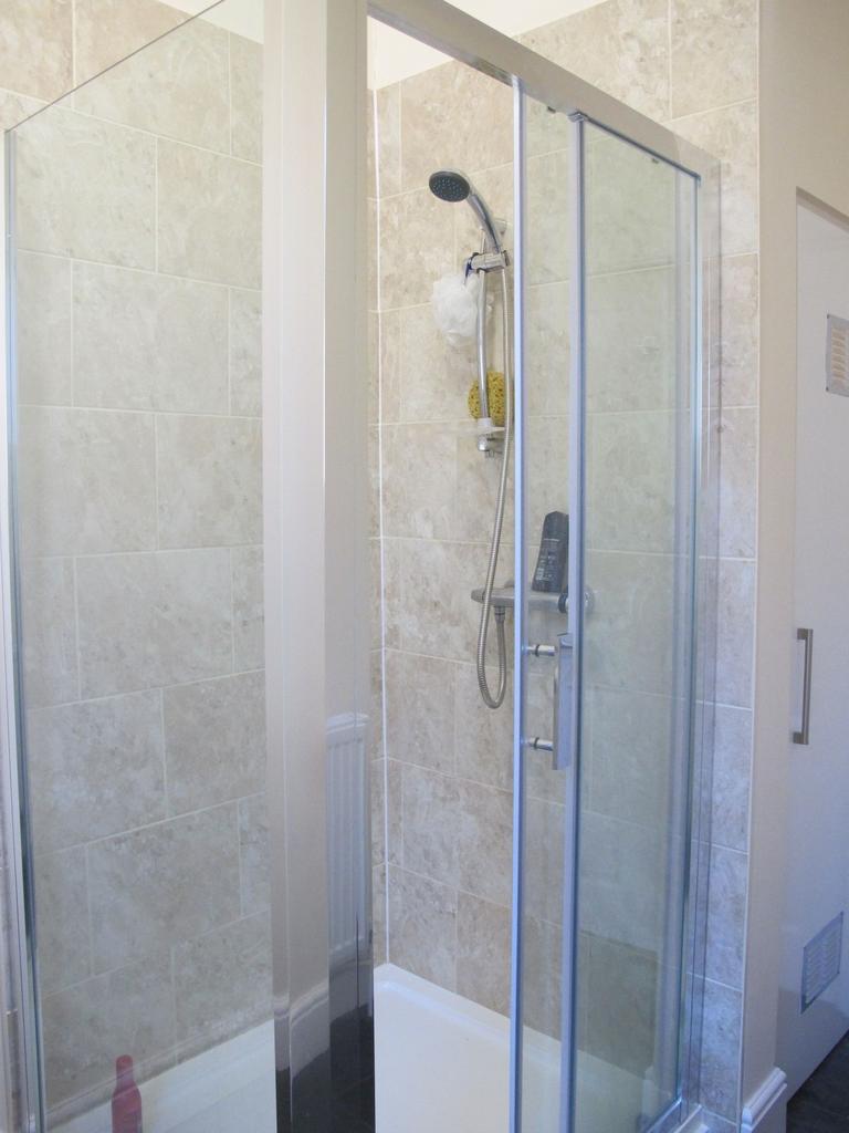 Bright tiled shower enclosure with sliding glas...
