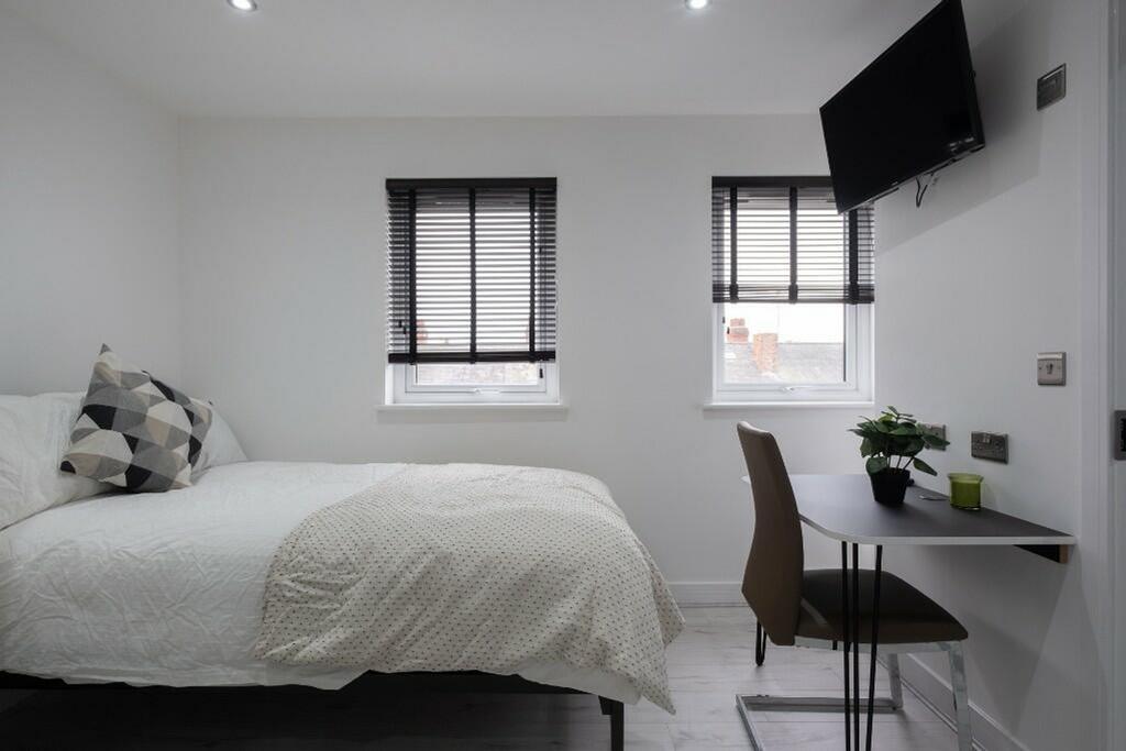 This cozy double bedroom features ample natural...