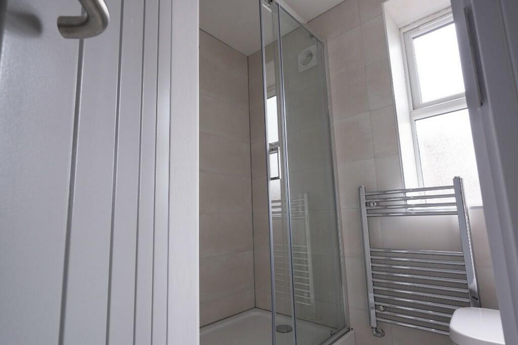 A modern bathroom featuring a sleek glass showe...