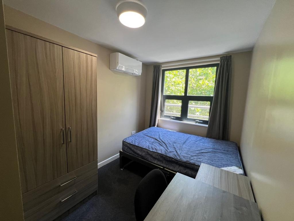 Neat single bedroom with a large window letting...