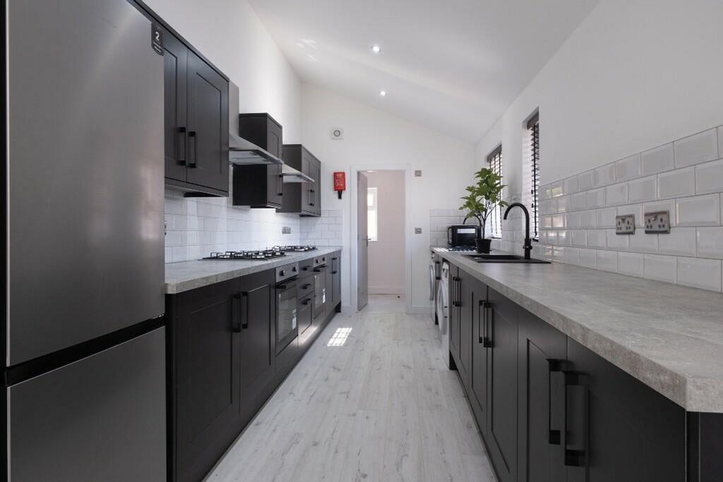 Modern kitchen featuring sleek black cabinetry,...
