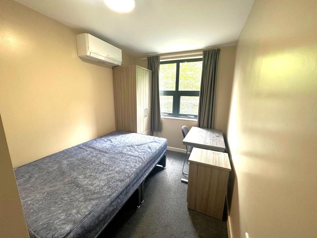Bright single bedroom with a large window, fitt...